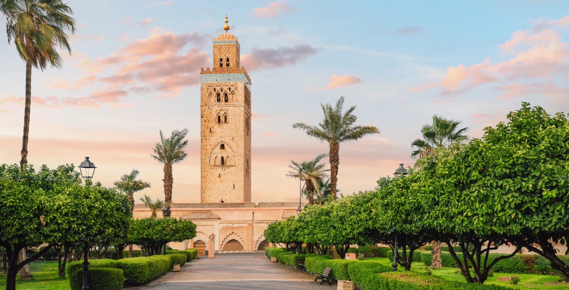 Koutoubia mosque minaret framed by palm trees and gardens in Marrakech, Morocco